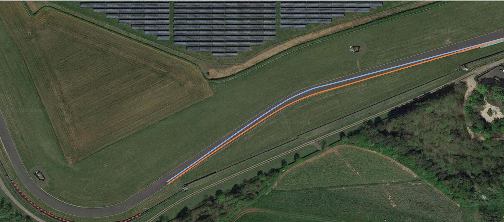 Aerial view of the Castle Combe Race Circuit in the UK with a blue and orange line painted on the track surface.